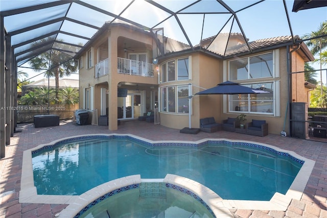 view of swimming pool with a pool with connected hot tub, ceiling fan, glass enclosure, outdoor lounge area, and a patio area