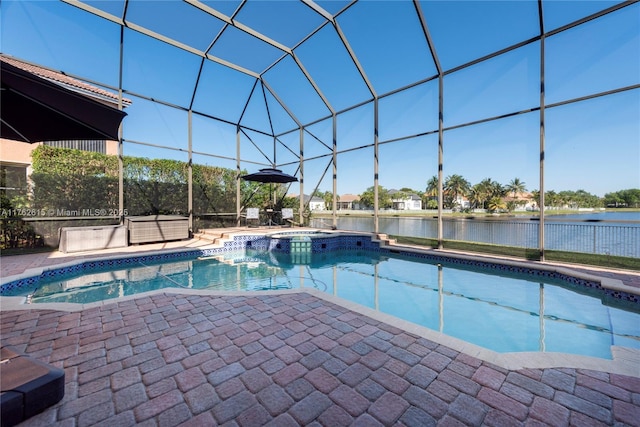 view of pool with a patio area, glass enclosure, a pool with connected hot tub, and a water view