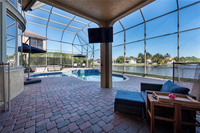 pool featuring glass enclosure, a patio, and a water view