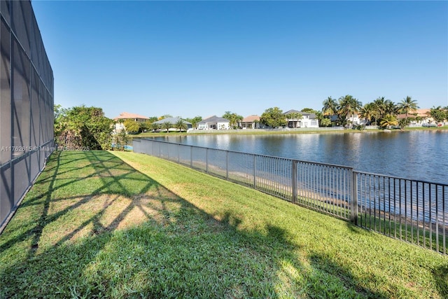 view of yard with a residential view, glass enclosure, a fenced backyard, and a water view