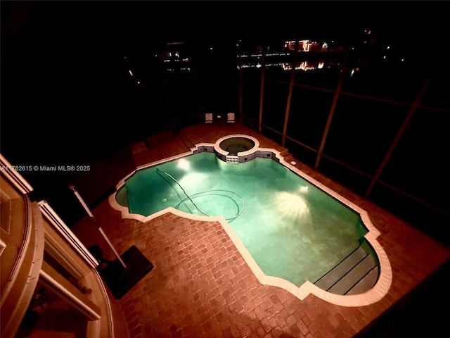 pool at twilight featuring a patio area and a pool with connected hot tub