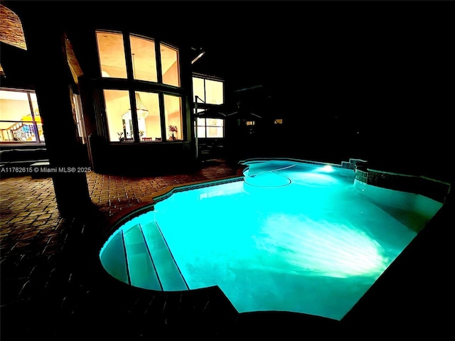 pool at twilight with an outdoor pool and a patio