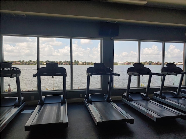 workout area featuring visible vents, a healthy amount of sunlight, and a water view