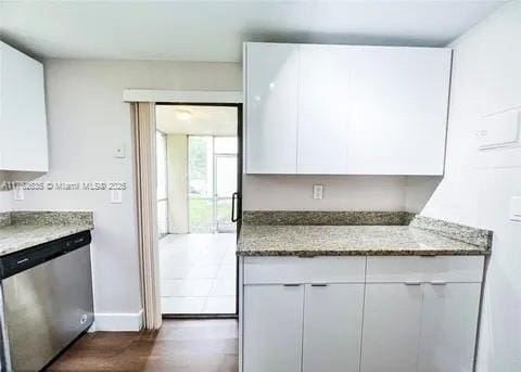 kitchen featuring stainless steel dishwasher, dark wood finished floors, white cabinets, baseboards, and light stone countertops