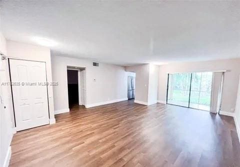 empty room featuring visible vents, baseboards, and wood finished floors