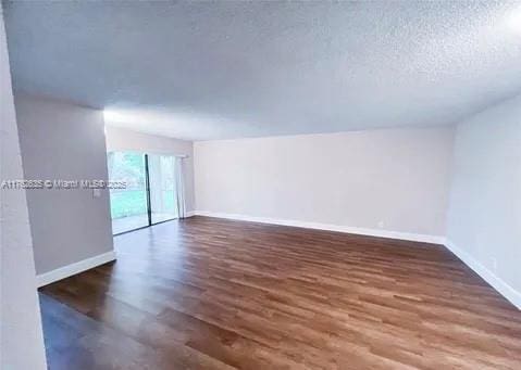 empty room featuring baseboards, a textured ceiling, and wood finished floors