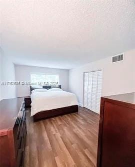 bedroom with visible vents, a textured ceiling, and wood finished floors