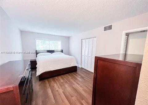 bedroom with visible vents, a textured ceiling, and wood finished floors