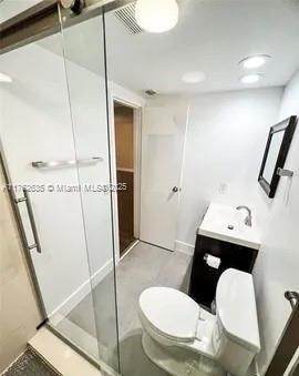 full bathroom featuring visible vents, a shower stall, toilet, and vanity