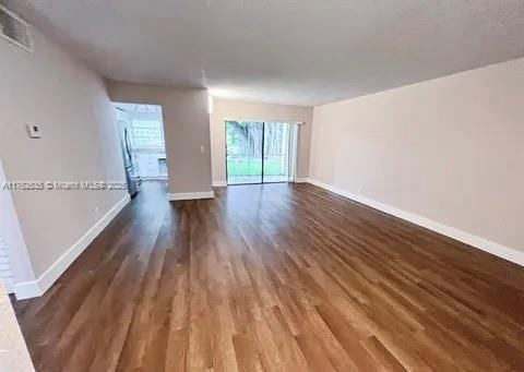 unfurnished living room featuring visible vents, wood finished floors, and baseboards