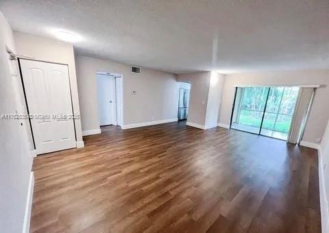 spare room with visible vents, baseboards, and wood finished floors