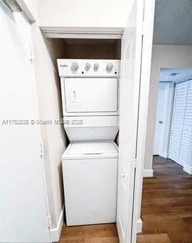 laundry room featuring stacked washer and dryer, wood finished floors, and laundry area