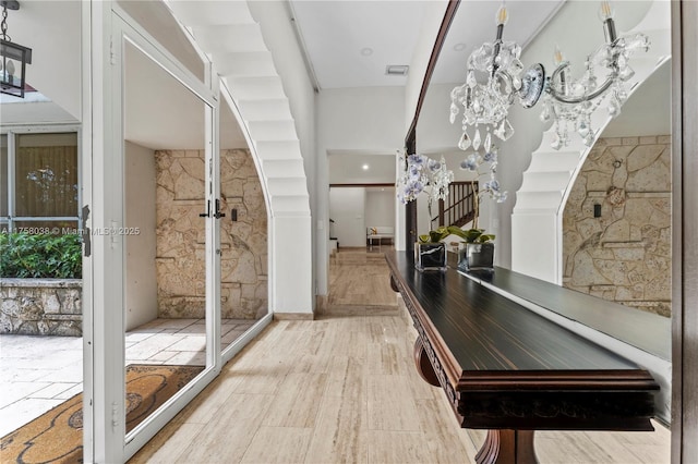 interior space with visible vents, a chandelier, stairs, french doors, and wood finished floors