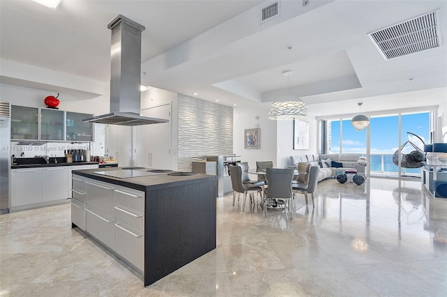 18201 Collins Ave Unit 4404, Sunny Isles Beach, FL 33160 - kitchen featuring island exhaust hood, dark countertops, modern cabinets, a raised ceiling, and a center island