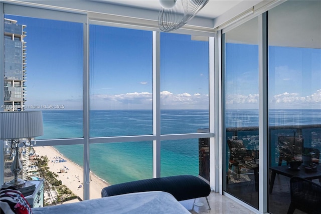 sunroom with a water view and a view of the beach