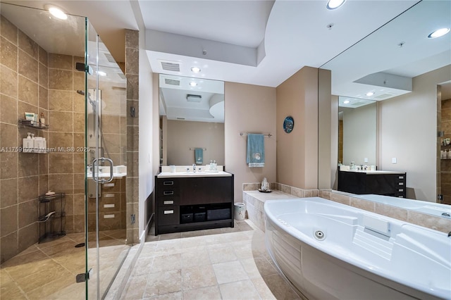 bathroom featuring visible vents, two vanities, a sink, a shower stall, and a jetted tub