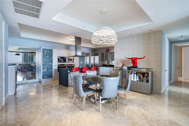 dining room with a tray ceiling and visible vents