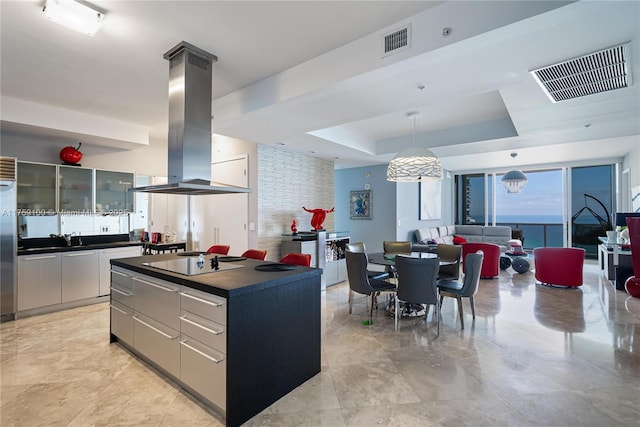 kitchen featuring dark countertops, black electric cooktop, island exhaust hood, and visible vents