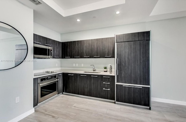 kitchen with modern cabinets, a sink, recessed lighting, stainless steel appliances, and light countertops