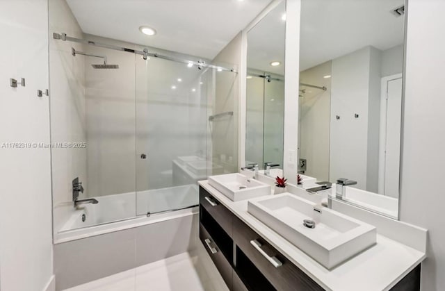 bathroom featuring enclosed tub / shower combo, visible vents, double vanity, and a sink