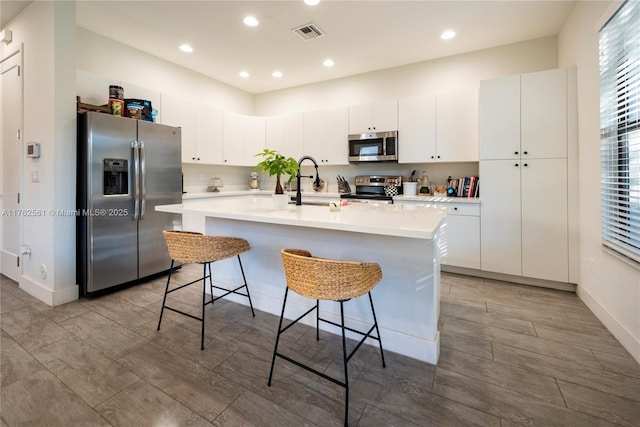 kitchen featuring visible vents, light countertops, a kitchen bar, appliances with stainless steel finishes, and a sink