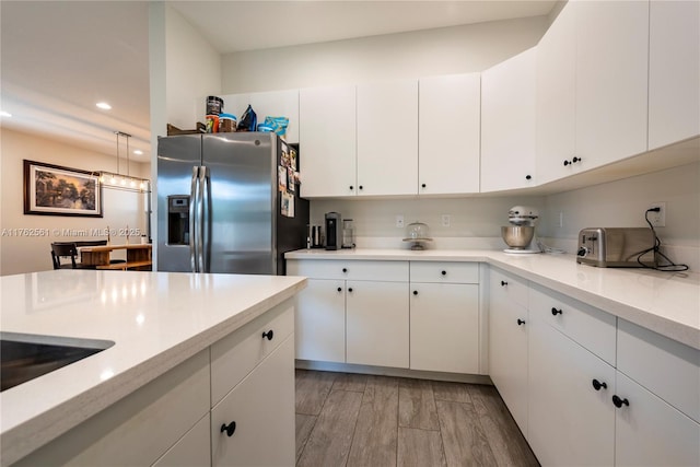 kitchen featuring stainless steel fridge, white cabinets, light countertops, and light wood-style floors