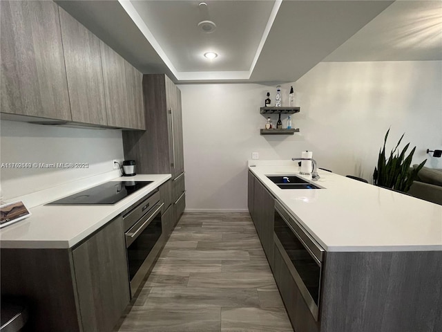 kitchen featuring open shelves, a sink, light countertops, stainless steel oven, and modern cabinets