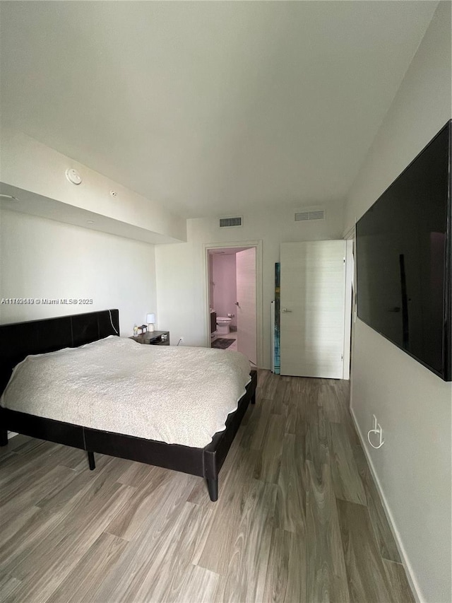 bedroom with visible vents, baseboards, and wood finished floors