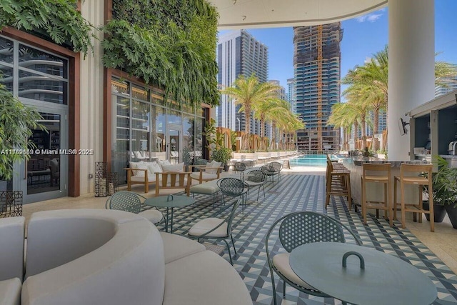 view of patio / terrace featuring outdoor dining space, a view of city, outdoor lounge area, and a community pool