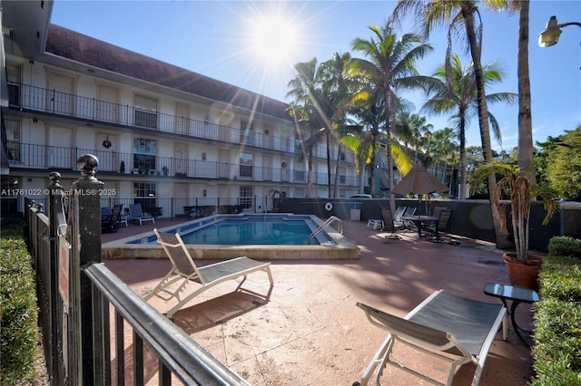 community pool with a patio and fence