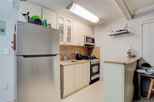 kitchen featuring backsplash, stainless steel appliances, a textured wall, a textured ceiling, and a sink