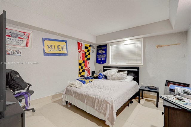 bedroom with a textured wall, baseboards, and a textured ceiling