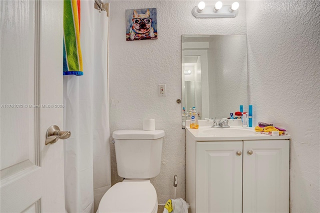 bathroom with vanity, a shower with curtain, toilet, and a textured wall