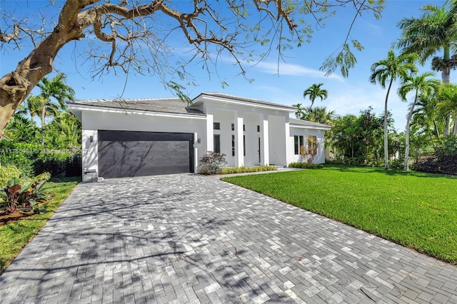 view of front of house featuring stucco siding, decorative driveway, a front yard, and an attached garage