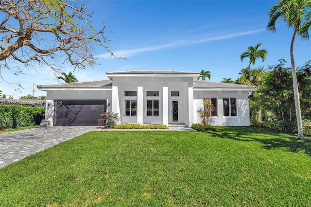 view of front of property with decorative driveway, a front yard, an attached garage, and stucco siding