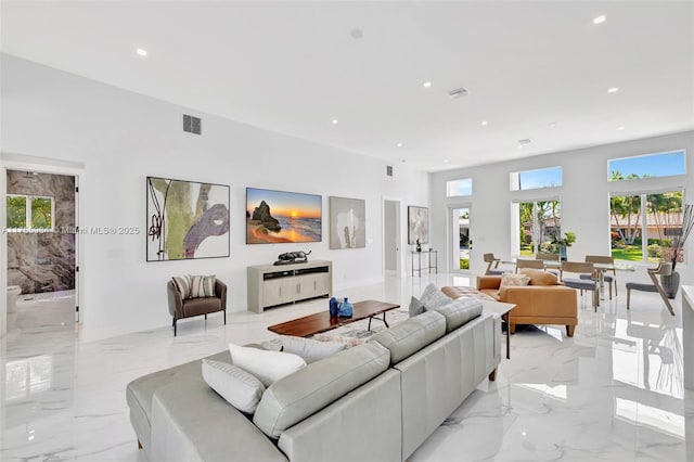 living area with recessed lighting, visible vents, and marble finish floor