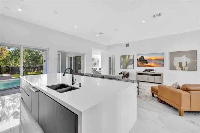 kitchen featuring visible vents, marble finish floor, modern cabinets, a sink, and open floor plan