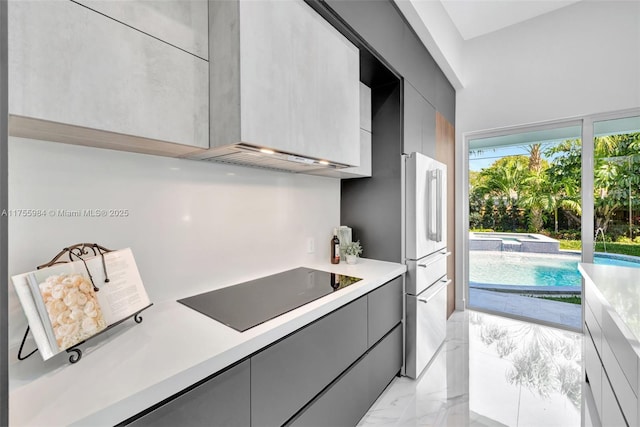 kitchen featuring black electric stovetop, light countertops, gray cabinets, marble finish floor, and modern cabinets