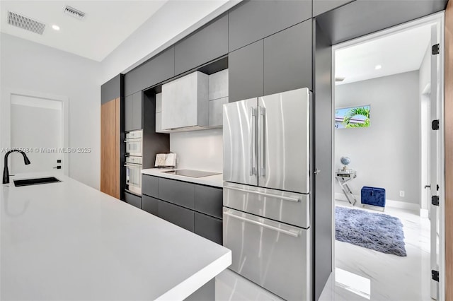 kitchen featuring visible vents, stainless steel appliances, light countertops, and a sink