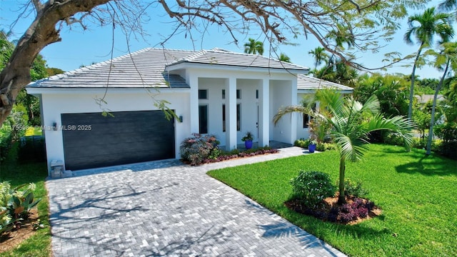 4440 NE 15th Ter, Oakland Park, FL 33334 - view of front facade featuring a front yard, stucco siding, an attached garage, a tiled roof, and decorative driveway