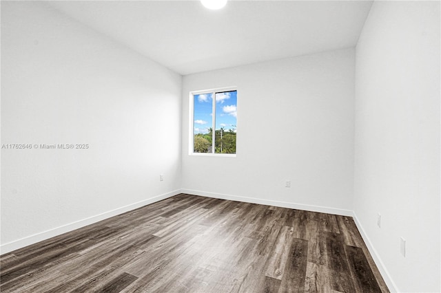 unfurnished room featuring baseboards and dark wood-style floors