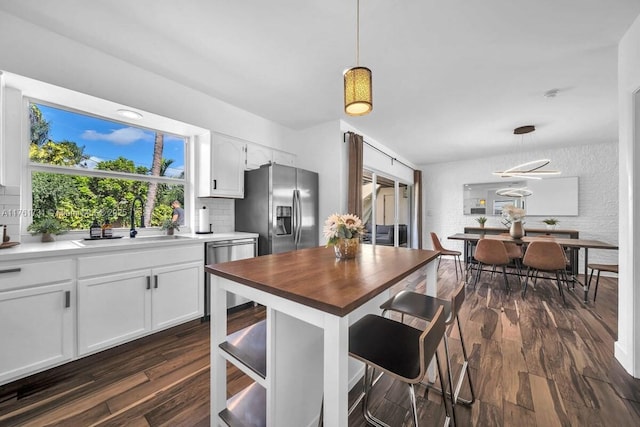 kitchen with dark wood-type flooring, a sink, backsplash, stainless steel appliances, and white cabinets