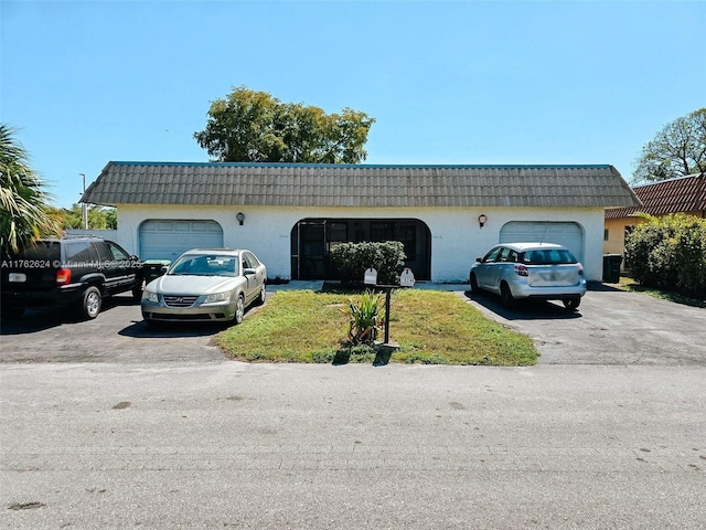 view of front facade with a tile roof, mansard roof, and driveway