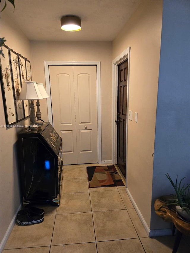 doorway to outside featuring light tile patterned flooring and baseboards