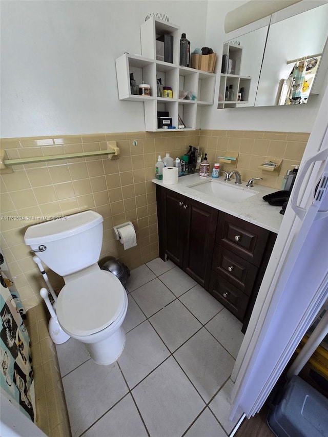 bathroom featuring tile patterned floors, a wainscoted wall, toilet, tile walls, and vanity