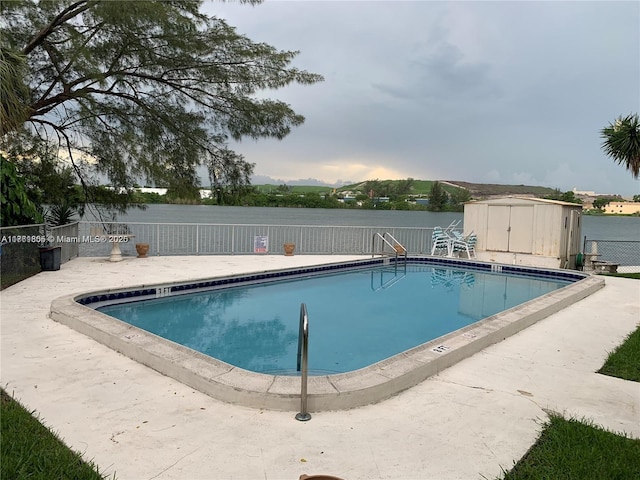 pool featuring a storage unit, an outbuilding, and fence