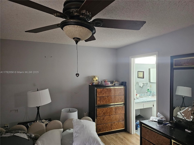 bedroom with connected bathroom, a ceiling fan, light wood finished floors, and a textured ceiling