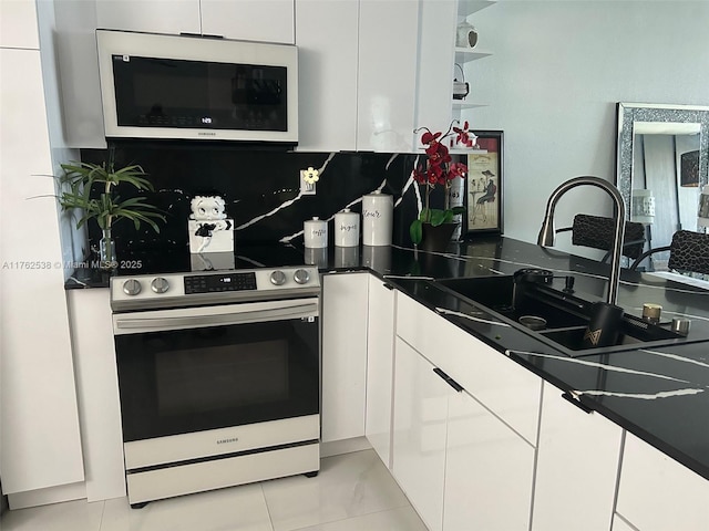 18555 NE 14th Ave Unit 609, Miami, FL 33179 - kitchen featuring stainless steel range with electric stovetop, white cabinets, modern cabinets, white microwave, and backsplash