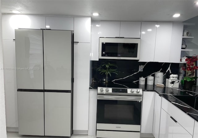 18555 NE 14th Ave Unit 609, Miami, FL 33179 - kitchen featuring stainless steel electric range, white cabinetry, white microwave, and freestanding refrigerator