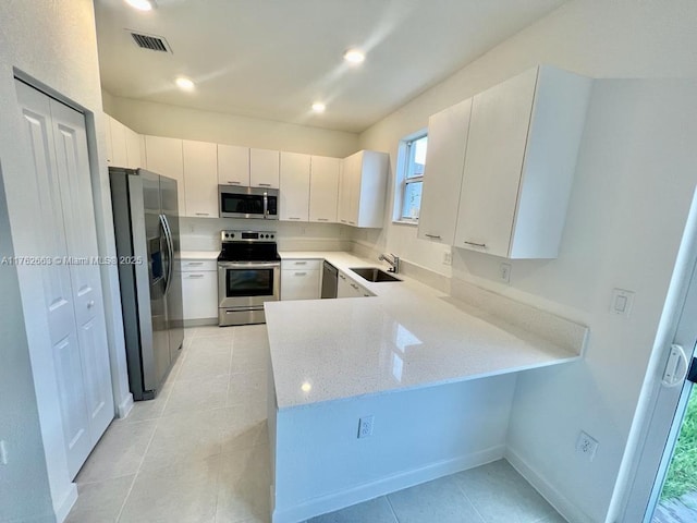 kitchen featuring visible vents, a sink, recessed lighting, stainless steel appliances, and a peninsula